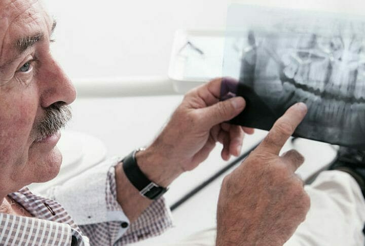 Elderly man discussing x-ray picture with dentist